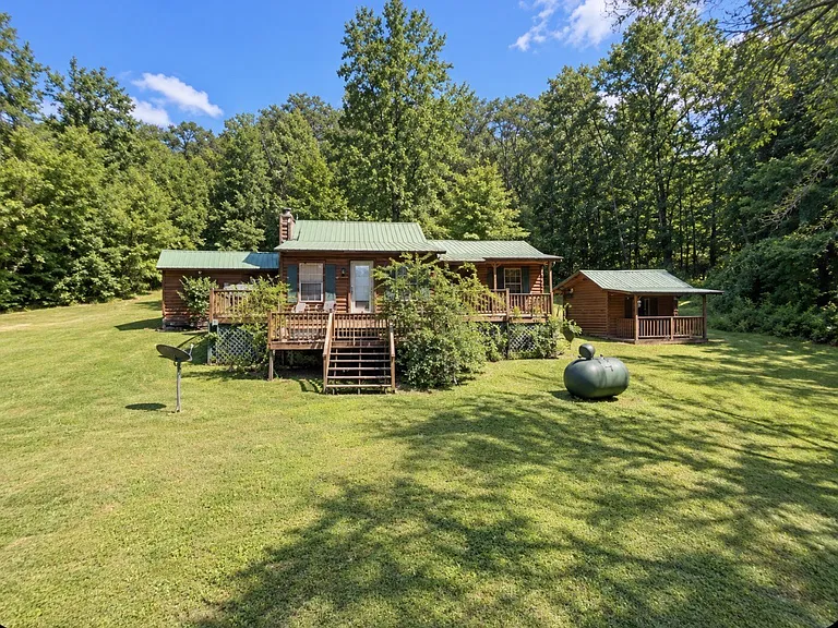 Tennessee Ridge, Tennessee Log Cabin on 5.12 Acres — 3 Bedrooms, 1 Bathroom, 1,487 Sq Ft, Creek, Storm Shelter, and Outbuildings for $110,000
